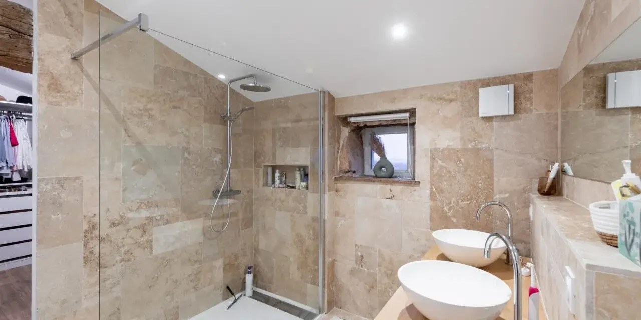 Salle de bain moderne avec une belle installation douche, deux lavabos et un dressing ouvert.