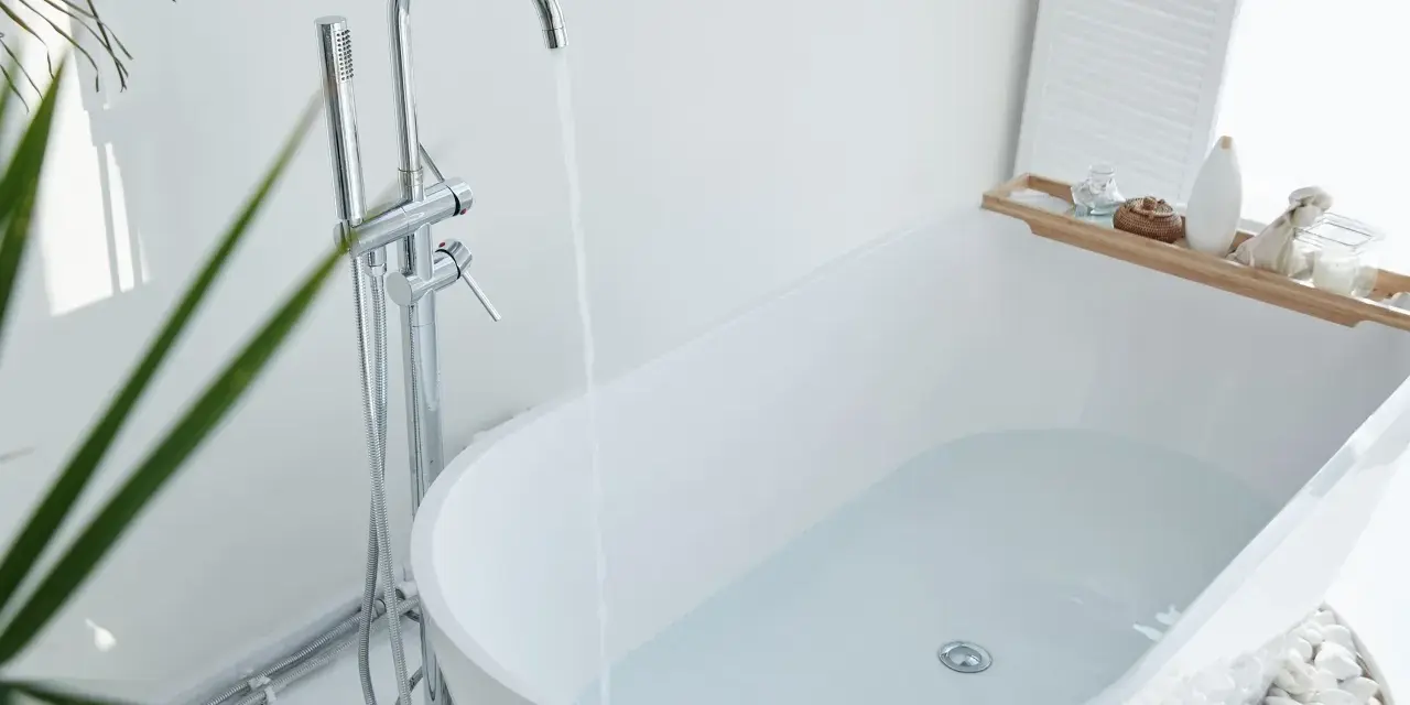 Baignoire moderne remplie d'eau, robinetterie chromée. Idéal pour changer la bonde baignoire sans trappe.