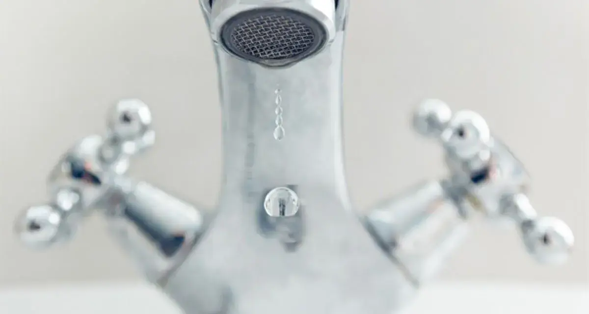 Gouttes d'eau tombant d'un robinet chromé. Comprendre la différence entre mitigeur et mélangeur pour une meilleure gestion de l'eau.