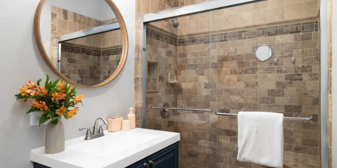 Salle de bain moderne avec douche carrelée, lavabo et miroir rond. Idéal pour nettoyer VMC et profiter d'un espace sain.