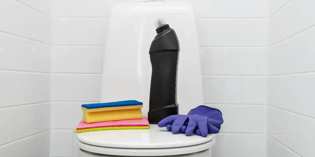 Produits de nettoyage pour les toilettes : une bouteille de produit, des éponges et des gants violets. Une astuce de grand-mère pour détartrer les wc.
