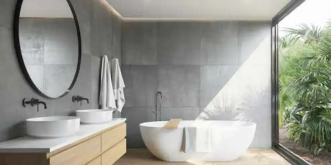 Salle de bain moderne avec baignoire îlot, double vasque et grande fenêtre donnant sur la végétation. L'étanchéité entre bac à douche et mur est assurée par des joints discrets.