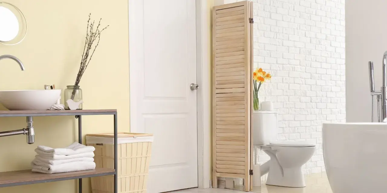 Un paravent en bois crée une séparation toilette salle de bain, cachant le WC derrière une porte blanche.