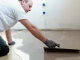 Un ouvrier applique du ragréage autonivelant sur un sol, créant une surface lisse et uniforme.