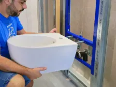 Un homme installe un bidet blanc, un élément essentiel pour une hygiène intime.