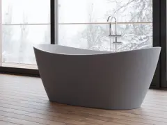 Baignoire îlot moderne, avec robinetterie chromée, devant une grande fenêtre donnant sur un paysage hivernal. Les inconvénients de ce type de baignoire sont son encombrement et la nécessité d'une installation spécifique.