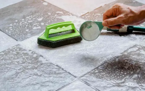 Nettoyer un carrelage mat et poreux avec une brosse et une poudre nettoyante.