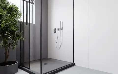 Douche surélevée pour évacuation, avec une paroi en verre et un robinet moderne. Un arbre vert apporte une touche de nature.