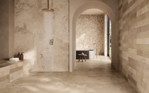Douche moderne avec carrelage effet pierre naturelle. Quel carrelage pour salle de bain ? Ce choix de tons chauds et de textures variées crée une ambiance zen et luxueuse.