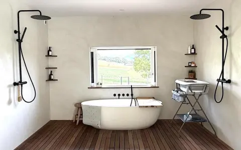 Une **salle de bain intemporelle** avec baignoire îlot, deux douches murales, et une vue sur la campagne.