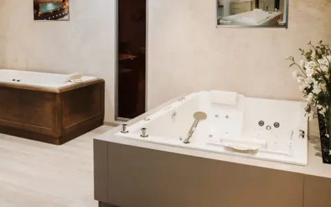 Deux baignoires modernes, une habillée de bois, l'autre d'un revêtement gris, illustrent comment habiller une baignoire avec style.