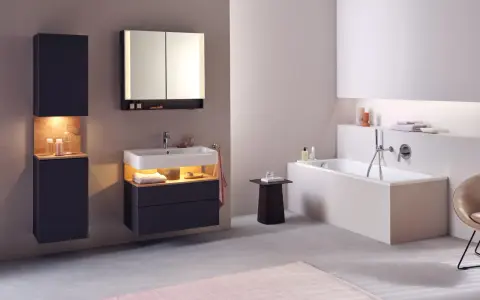 Salle de bain moderne avec baignoire, lavabo et meubles suspendus. Le sol en béton poli et le carrelage mural clair facilitent le nettoyage.