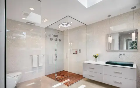 Salle de bain moderne avec douche italienne spacieuse, sol en bois, murs en mosaïque et lavabo design.