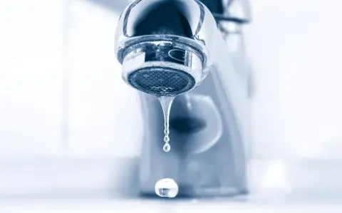 Gouttelettes d'eau tombant d'un robinet de salle de bain qui fuit. Un petit désagrément qui coûte cher.