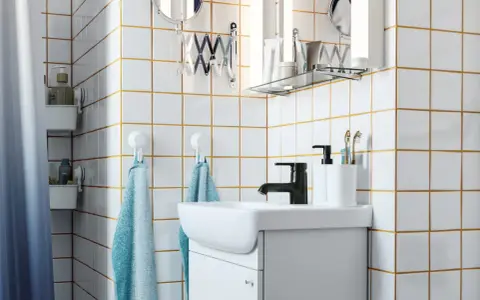 Salle de bain moderne avec carrelage blanc joint gris, lavabo, robinetterie noire et accessoires pratiques.