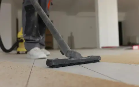Nettoyage de carrelage après chantier : un aspirateur passe sur le sol poussiéreux.