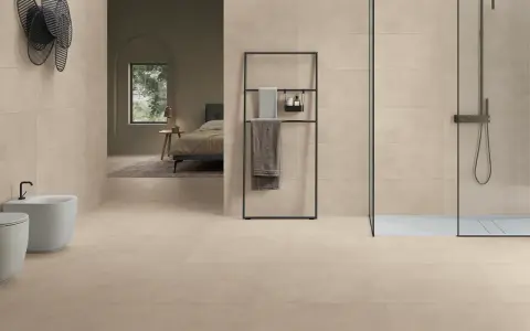 Salle de bain moderne avec bidet, douche et lit visible au loin, le tout revêtu de grès cérame émaillé.