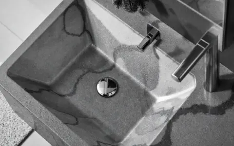Évier en béton gris avec des veines sombres, robinetterie moderne. La différence évier lavabo est subtile, mais ici, c'est un lavabo design.