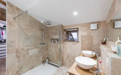 Salle de bain moderne avec une belle installation douche, deux lavabos et un dressing ouvert.
