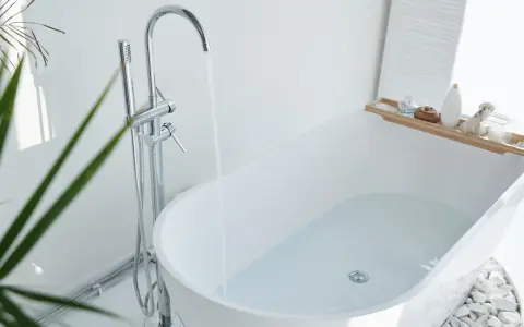 Baignoire moderne remplie d'eau, robinetterie chromée. Idéal pour changer la bonde baignoire sans trappe.