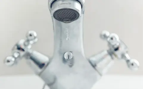 Gouttes d'eau tombant d'un robinet chromé. Comprendre la différence entre mitigeur et mélangeur pour une meilleure gestion de l'eau.