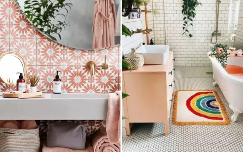 Une salle de bain bohème avec des carreaux floraux roses, un tapis arc-en-ciel et une baignoire remplie d'eau orangée.