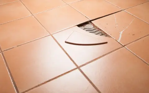 Carrelage orange avec une tuile cassée et un éclat à réparer.
