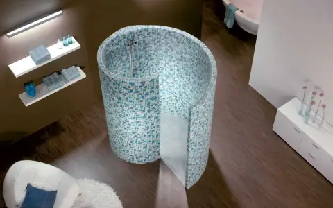 Une douche escargot aux mosaïques bleues et vertes, avec une baignoire et un fauteuil dans une salle de bain moderne.