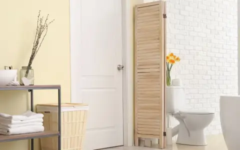 Un paravent en bois crée une séparation toilette salle de bain, cachant le WC derrière une porte blanche.