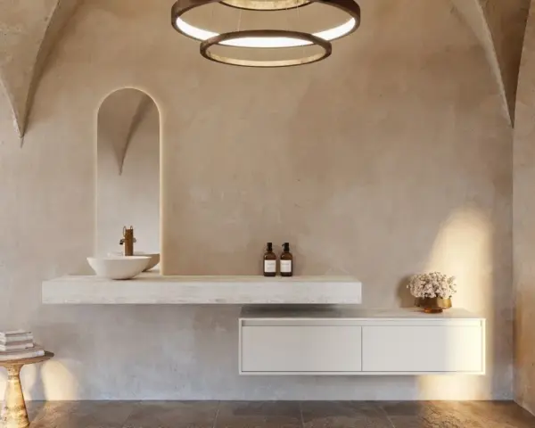 Une salle de bain nature aux murs texturés, avec un lavabo suspendu, un miroir arqué rétroéclairé et des touches végétales.