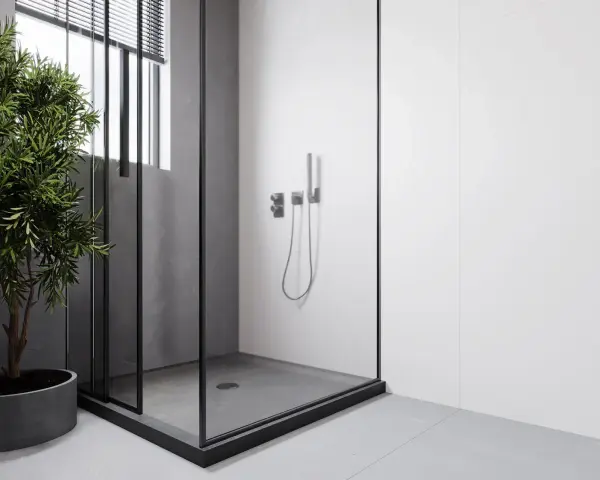 Douche surélevée pour évacuation, avec une paroi en verre et un robinet moderne. Un arbre vert apporte une touche de nature.