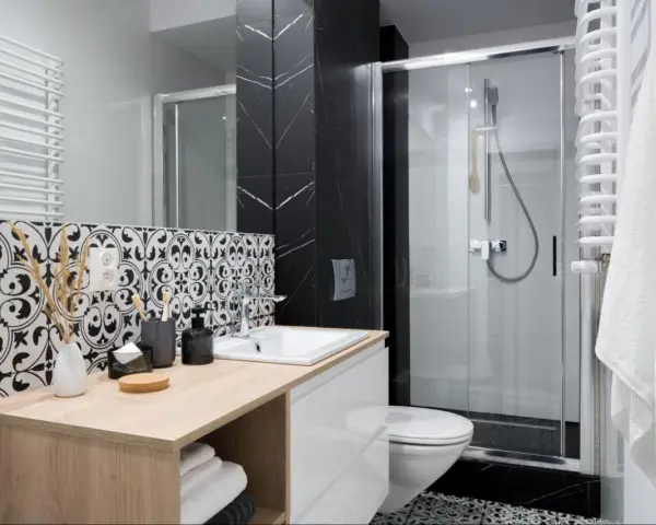 Élégante petite salle de bain italienne avec carrelage noir et blanc, douche moderne et meuble vasque en bois clair.
