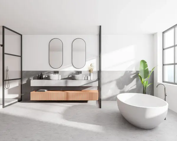 Salle de bain moderne avec baignoire îlot, double vasque et douche. Le sol en béton ciré, un carrelage sans joint, crée une ambiance épurée et contemporaine.