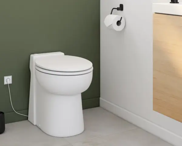 Toilettes modernes avec un sanibroyeur discret, dont le fonctionnement est assuré par une prise électrique visible.