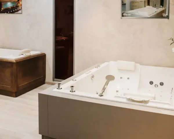 Deux baignoires modernes, une habillée de bois, l'autre d'un revêtement gris, illustrent comment habiller une baignoire avec style.