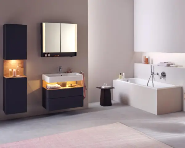 Salle de bain moderne avec baignoire, lavabo et meubles suspendus. Le sol en béton poli et le carrelage mural clair facilitent le nettoyage.