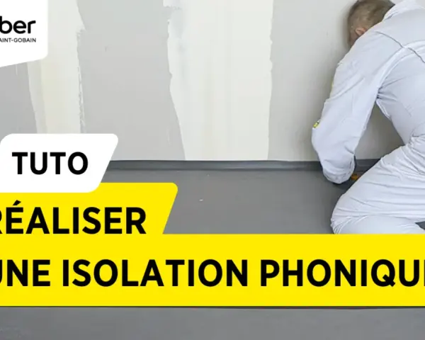 Tuto : réaliser une isolation phonique sur carrelage existant. Un ouvrier en combinaison blanche installe un revêtement gris au sol.