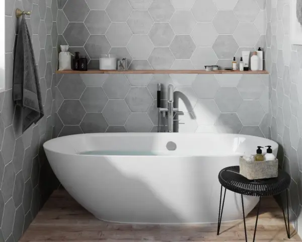 Salle de bain moderne avec baignoire îlot, carrelage mural hexagonal gris et étagère en bois.