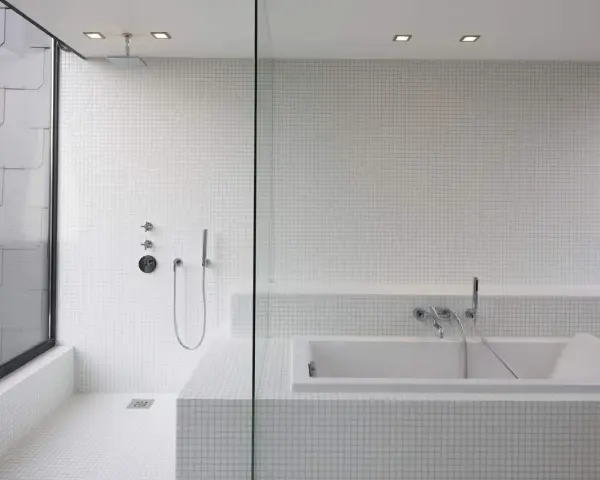 Salle de bain moderne avec douche à l'italienne et baignoire îlot, le tout revêtu de petites mosaïques blanches.