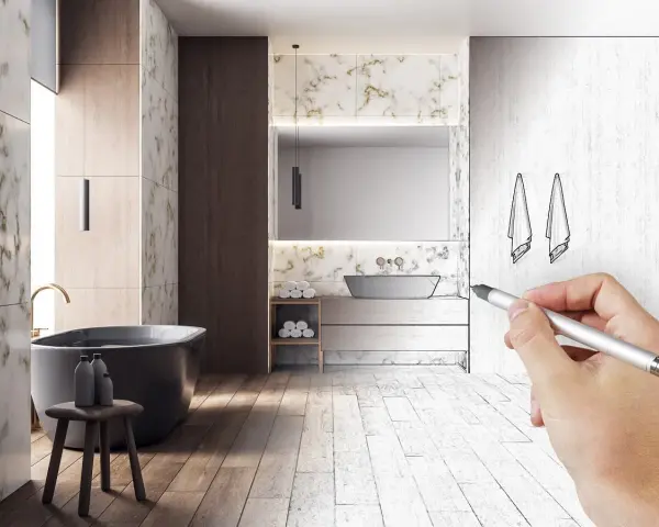 Main d'un architecte esquissant le schema d'evacuation baignoire dans une salle de bain moderne.