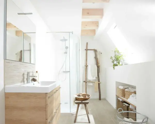 Salle de bain lumineuse avec douche, lavabo en bois clair et paniers de rangement. Un style de wet room épuré et naturel.