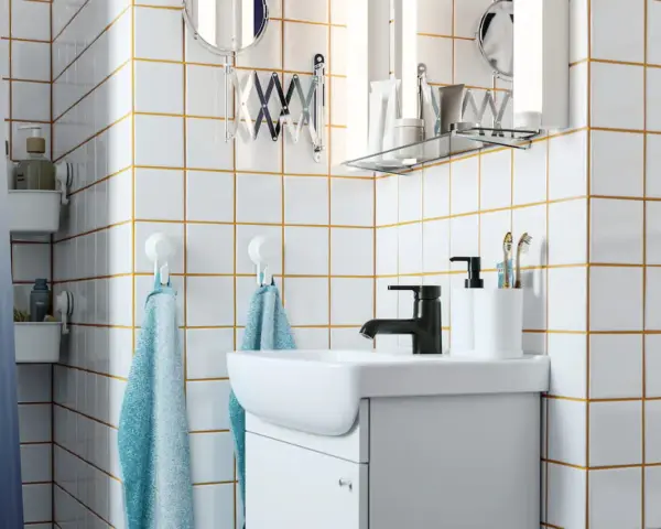 Salle de bain moderne avec carrelage blanc joint gris, lavabo, robinetterie noire et accessoires pratiques.