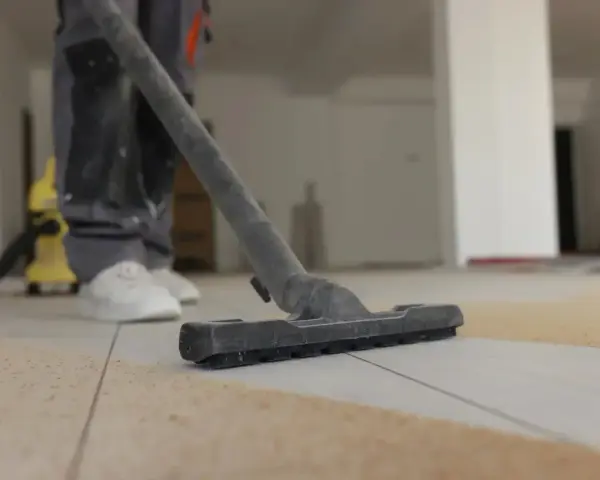 Nettoyage de carrelage après chantier : un aspirateur passe sur le sol poussiéreux.