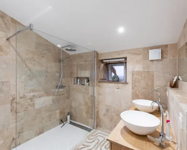 Salle de bain moderne avec une belle installation douche, deux lavabos et un dressing ouvert.