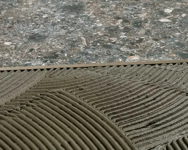Pose de mortier pour un double encollage de carrelage. Les mains d'un carreleur préparent la surface.