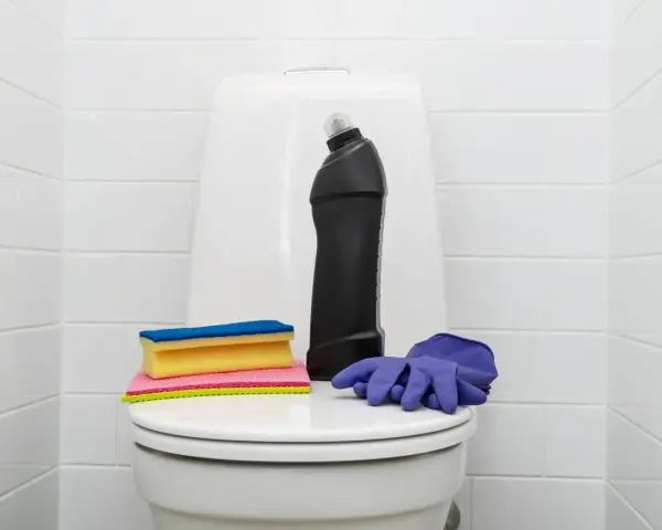 Produits de nettoyage pour les toilettes : une bouteille de produit, des éponges et des gants violets. Une astuce de grand-mère pour détartrer les wc.