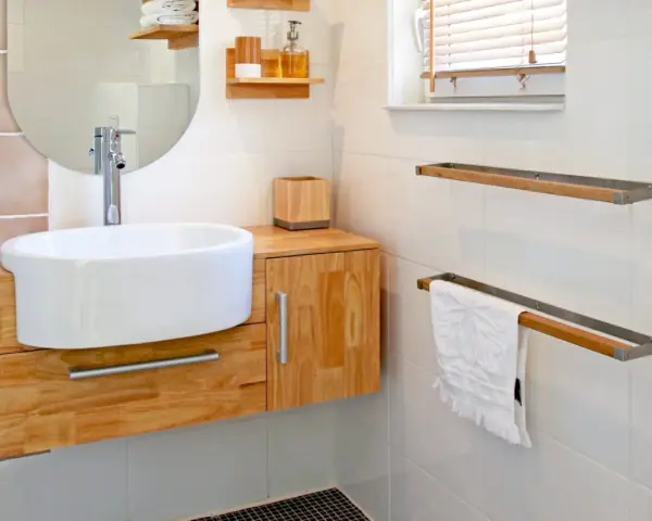 Meuble de salle de bain en bois clair, avec vasque blanche et robinetterie moderne. La hauteur du meuble est idéale pour un accès facile.