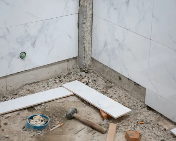 Travaux de pose de faience salle de bain : des carreaux de marbre blanc sont prêts à être installés, avec des outils au sol.