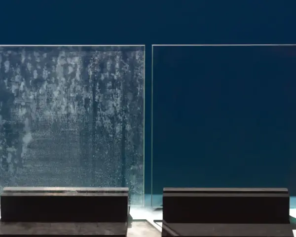 Comparaison de deux parois de douche : l'une est recouverte de dépôts calcaires incrustés, l'autre est parfaitement propre et transparente.