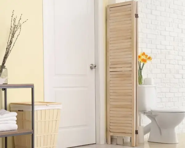 Un paravent en bois crée une séparation toilette salle de bain, cachant le WC derrière une porte blanche.